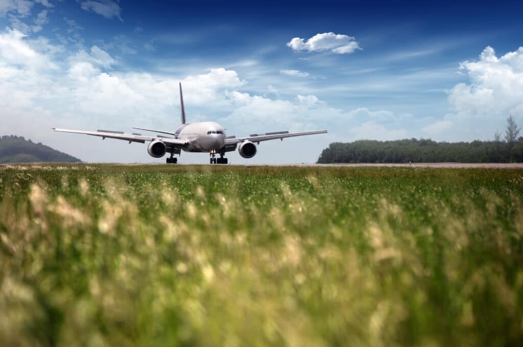 airplane landing on a green field with blue sky in the background