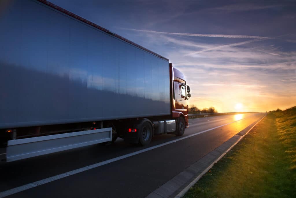 Red truck driving at sunset