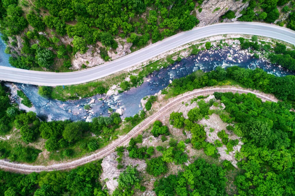 Aerial view  over mountain road and curves going through forest