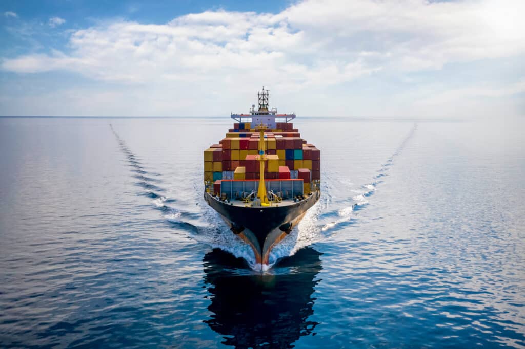 Aerial front view of a loaded container cargo vessel traveling