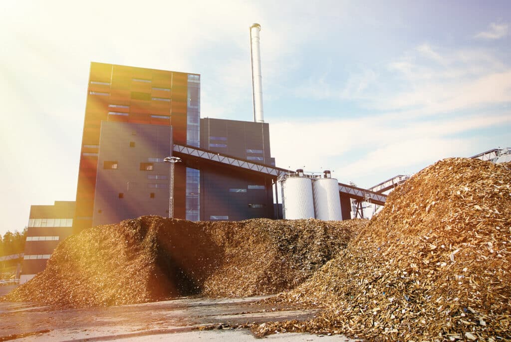 bio power plant with storage of wooden fuel (biomass) against blue sky