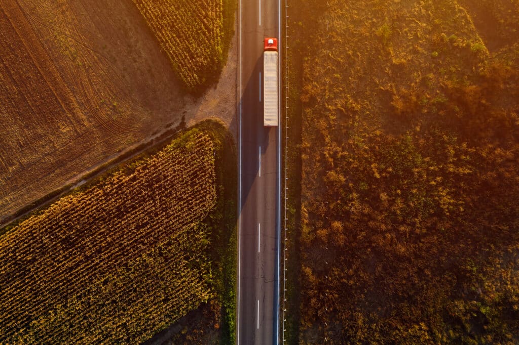 red truck driving on the highway top view with trees around the highway
